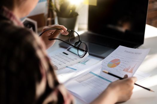 business woman analysis cost graph on work place. female working with laptop computer and calculator for finance.