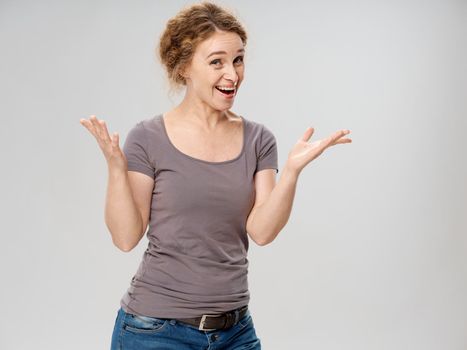 an elderly woman in a gray t-shirt and jeans gestures with her hands