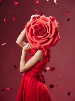 Woman in a red dress with a flower near her face and rose petals