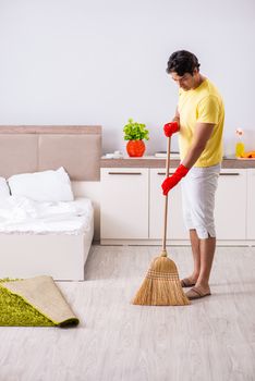Young handsome man cleaning in the bedroom