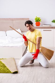Young handsome man cleaning in the bedroom