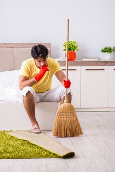 Young handsome man cleaning in the bedroom