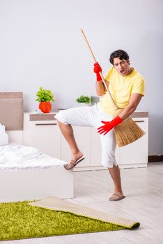 Young handsome man cleaning in the bedroom