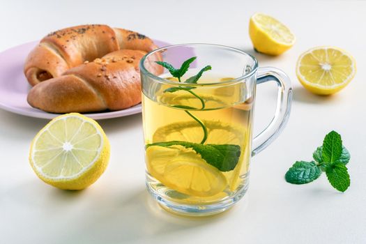 Close-up of green tea with lemon and mint in a glass cup. Tea party with rich bagels. Selective focus.