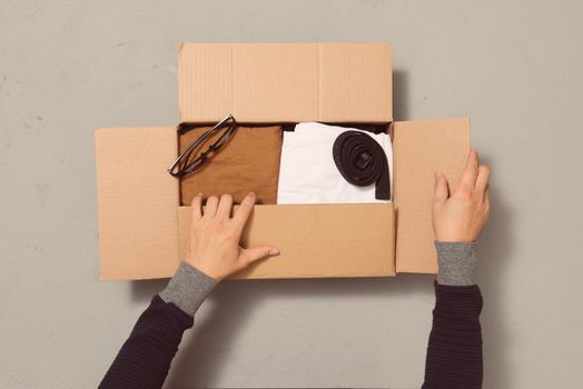 man putting different clothes in a carboad box. Clothes donation or reuse concept