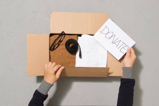 Man hands putting clothes to donate box