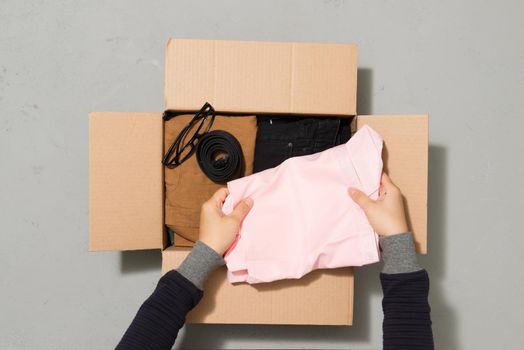 man putting different clothes in a carboad box. Clothes donation or reuse concept