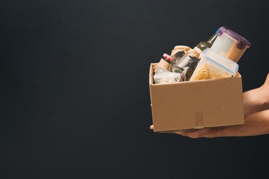 A young man volunteer is holding a donation box with foodstuffs.