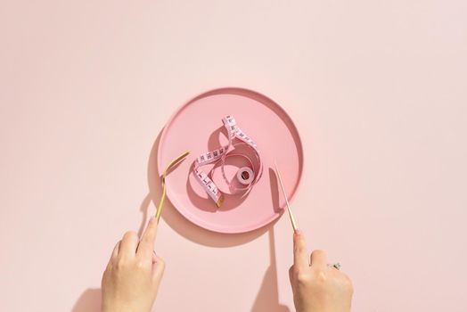 Empty plate with measuring tape, knife and fork. Diet food on a color table