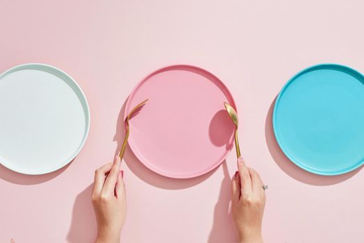 Restaurant and Food theme: the human hand show gesture on an empty three color plates on a pink background