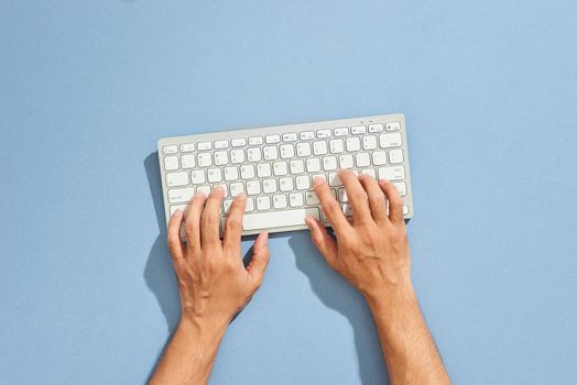 Hands typing computer keyboard. Top view