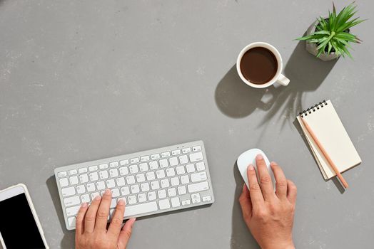 Businesman working is typing on computer keyboard and holding computer mouse on light background