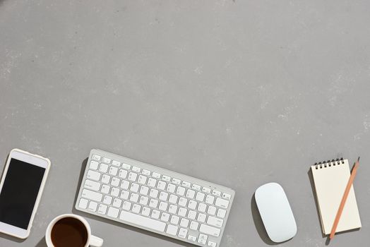 top view of office desk workspace with coffee cup, notebook, plastic plant, graphic tablet on gray background