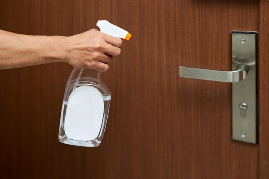 Man disinfecting the Door knob by spraying a white sanitizer from a bottle, Prevent covid19, corona virus.