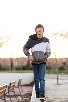 Stylish handsome teen boy wearing denim jacket and knit hat over city background close up