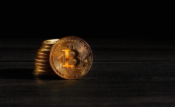 Leader in cryptocurrency bitcoin BTC on a top of coins against black wooden surface. Closeup golden coin with bitcoin logo. Stack of decentralized digital currency. Crypto payment. Electronic money