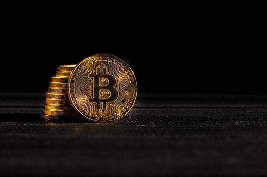 Leader in cryptocurrency bitcoin BTC on a top of coins against black wooden surface. Closeup golden coin with bitcoin logo. Stack of decentralized digital currency. Crypto payment. Electronic money