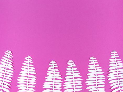 White paper cut leaves on a pink background.