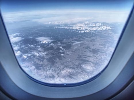 View of the rural landscape from plane window, selective focus. Island in ocean visible from low flyinf airplane