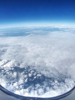 Clouds landscape through plane window, regular flight over south Europe and Middle terrain sea. Sunny spring day with fluffy clouds