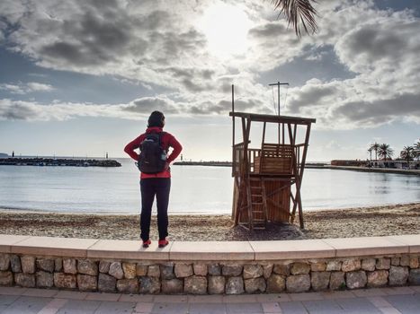 Traveler watch over bay to evening horizon.  Lifeguard Tower at Beach  Majorca island, winter trekking season.