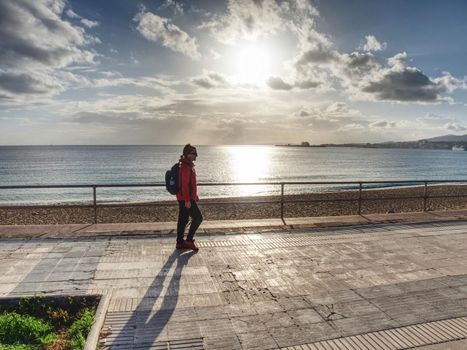 Young woman hiker with backpack on sunrise beach