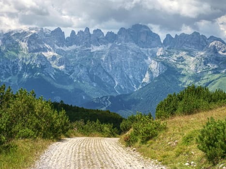Beutiful summer Alps mountains, clouds above peaks and forest in foreground,