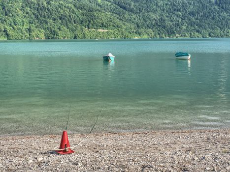 Beautiful high mountain lake with mountains around. The incredibly magic blue green lake with fishing boats or canoe