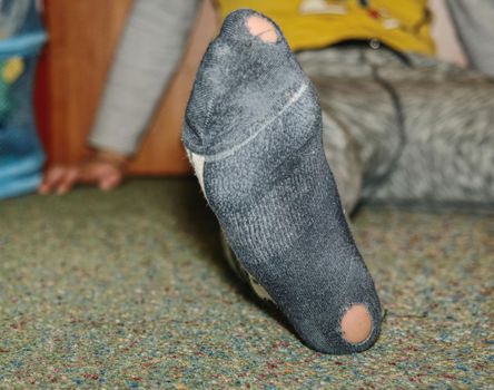 Worn socks with a hole and heel sticking out. Old worn clothes