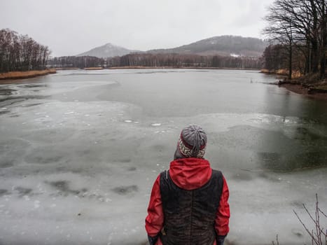 Woman sitting on a lake bank in the rain looking on water level