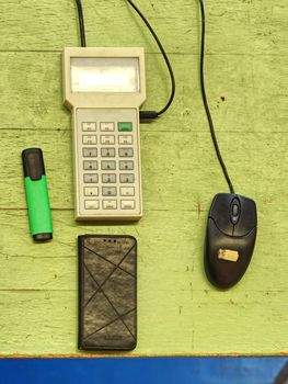 Data keyboard terminal on wooden board. Green highlighter and black cable. Key board of small remote control 