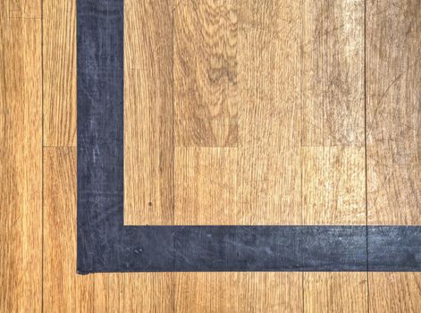 Hall floor in a gymnasium with diverse lines. Worn out wooden floor of sports hall with colorful marking lines. Schooll gym hall