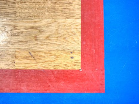 Red playfield line in blue square. Marks on fooden floor of sports gymnasium. Ground colorful marking lines