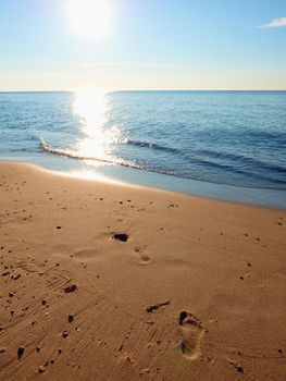 Natural footprints in beach sand. Traces on beach by smooth sea, coastline in summer 