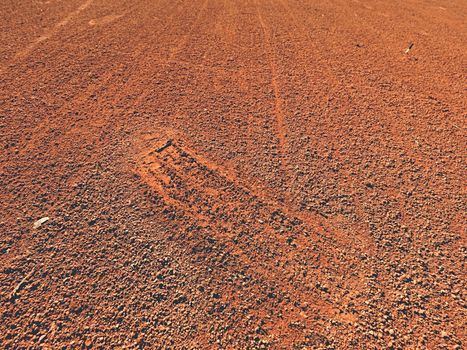 Detail with a sport shoe footprint on a tennis clay court. Dry light red crushed bricks surface on outdoor tennis ground