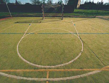 Empty outdoor handball playground, plastic hairy green surface on ground and white blue bounds lines. 