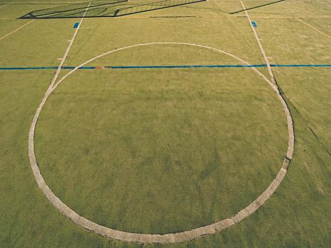Circle in middle of court. Empty outdoor handball playground, plastic light green surface on ground and white blue bounds lines.