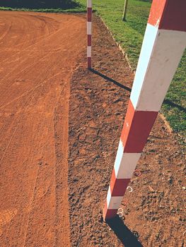 Detail of gate frame . Outdoor football or handball playground, light red clay. Red crushed bricks surface on ground