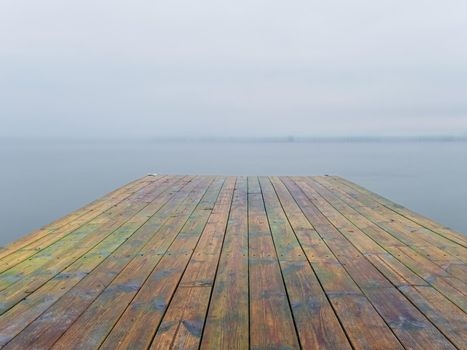 Abandoned wooden wharf mole in sea within sunrise. Gentle blue pink color of sky blurry waves on water level.