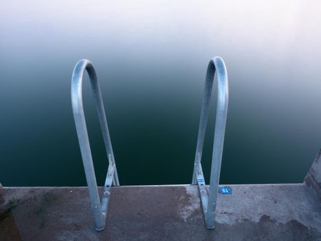 Swimming ladder from stainless steel for descent into sea water on pier. Silent bay ideal for children swim and play