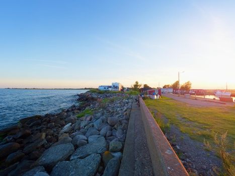 Small port at fishing village  with small fishing boats. Quiet bay at stony dam. Summer traveling in Sweden. Sunny evening.