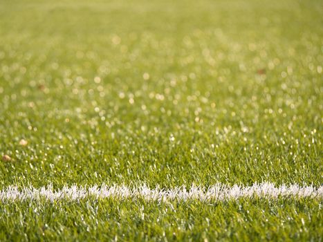 White line marks painted on artificial green turf background. Playfield border. Winter football playground with plastic grass.