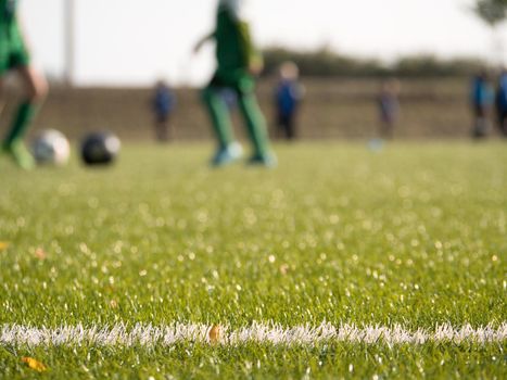 White line marks painted on artificial green turf background. Playfield border. Winter football playground with plastic grass.