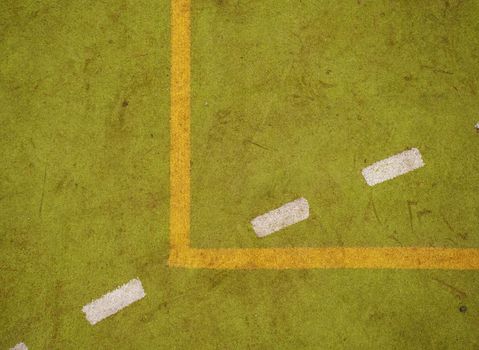 Border lines on court. Worn out green red hairy carpet on outside hanball playground. Floor of sports court with white marking lines.