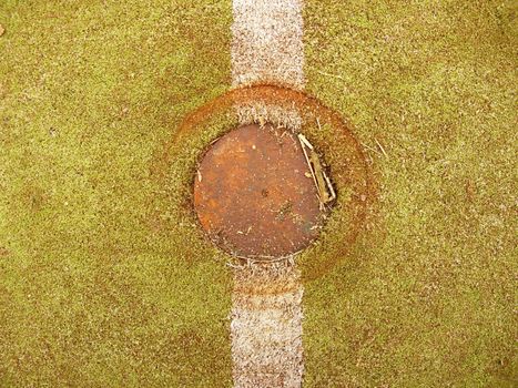 Line on poor small school football or handball field.  Worn out green red hairy tartan on outside hanball playground. Floor of sports court with white marking lines.