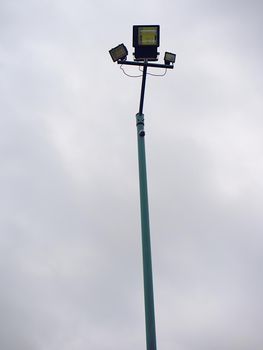 Lonely stadium light or lamp post with Union of light bulb stand alone with clould and blue sky.
