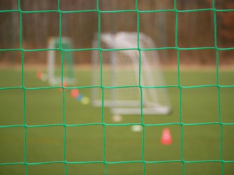 Soccer football net background over green grass and blurry stadium. Close up detail of a soccer net Footballsoccer field.  

