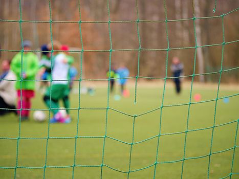 Football training.  Crossed soccer nets soccer football in goal net with grass on outdoor playground in the background.