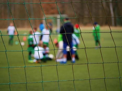 Football gate net. Soccer gate net. In blurry background stand players. Training of junior team. 