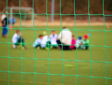 Football gate net. Soccer gate net. In blurry background stand players. Training of junior team. 